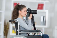 A woman in a wheelchair using a professional photography camera