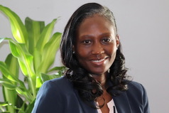 MOHS Director, Ernestina Simmons, in a navy blue blazer and a plant behind her