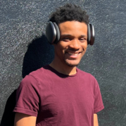 A young adult male wearing a burgundy tshirt and black headphones