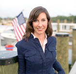 Photo of Sec. Haddaway-Riccio on dock in front of American flag
