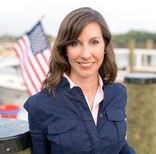 Photo of Sec. Haddaway-Riccio on dock in front of American flag
