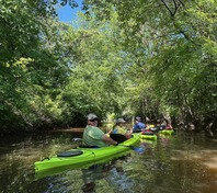 People kayak through a creek