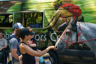 A mother and child pet a horse in front of the Mobile Visitor Center