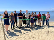 People cutting a ribbon on a beach