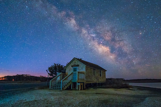 Milky way with boathouse and bay