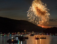 Fireworks above a lake with lighted boats on the water