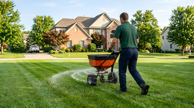 Professional Landscaper Applying Fertilizer with Broadcast Spreader on Lush Green Lawn | Residential Lawn Care