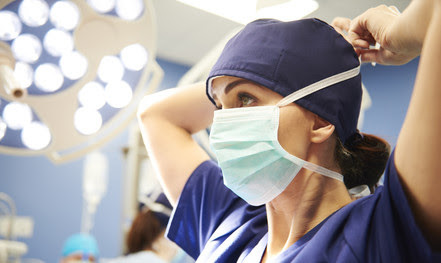A medical professional puts on a surgical mask.