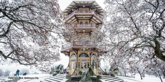 The Patterson Park Pagoda in Baltimore City, covered in white snow and framed by frosted, leafless winter trees.