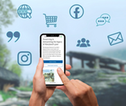 Hands holding a smartphone displaying the MHT website, surrounded by floating blue digital communication icons.