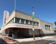 Art Deco building with a vertical SquashWise sign and a curved white canopy on a sunny street corner.