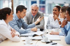 Stock image of individuals meeting around a table