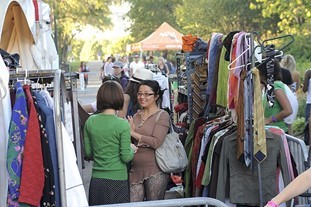two people shopping for clothes at an open-air market