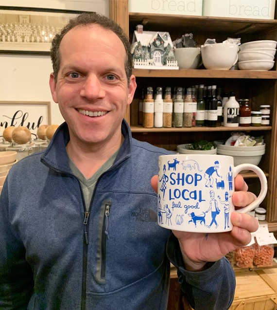 Council President Glass smiling at a pottery shop with a mug that says "shop local"