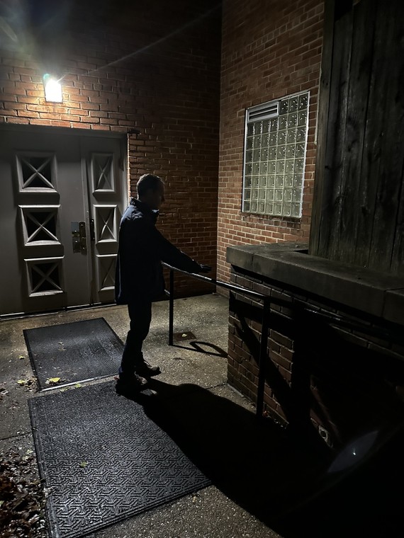 Council President Glass stands outside of a dark building at night during the Point in Time walk