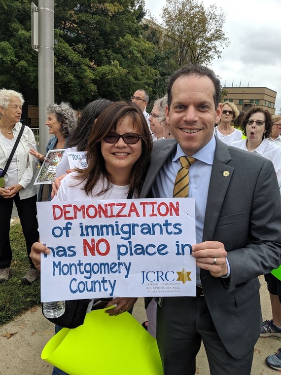 Council President Glass poses with Aryani Ong holding a sign supporting immigrant rights.