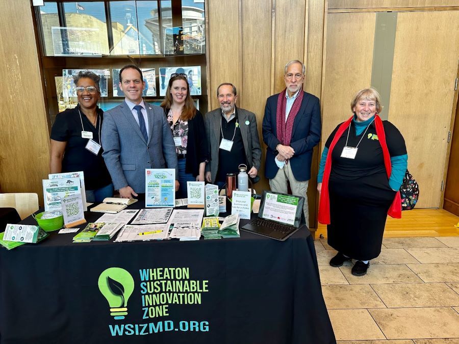 Council President Glass stands at a conference table with members of Wheaton Sustainable Innovation Zone