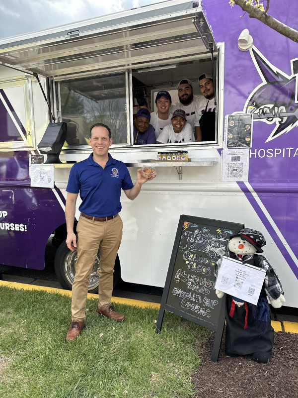 Council President Glass poses in front of the Rolling Raptor EduKitchen.