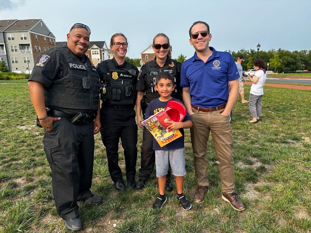 Council President Glass poses for a photo with 3 officers and a child at National Night Out.