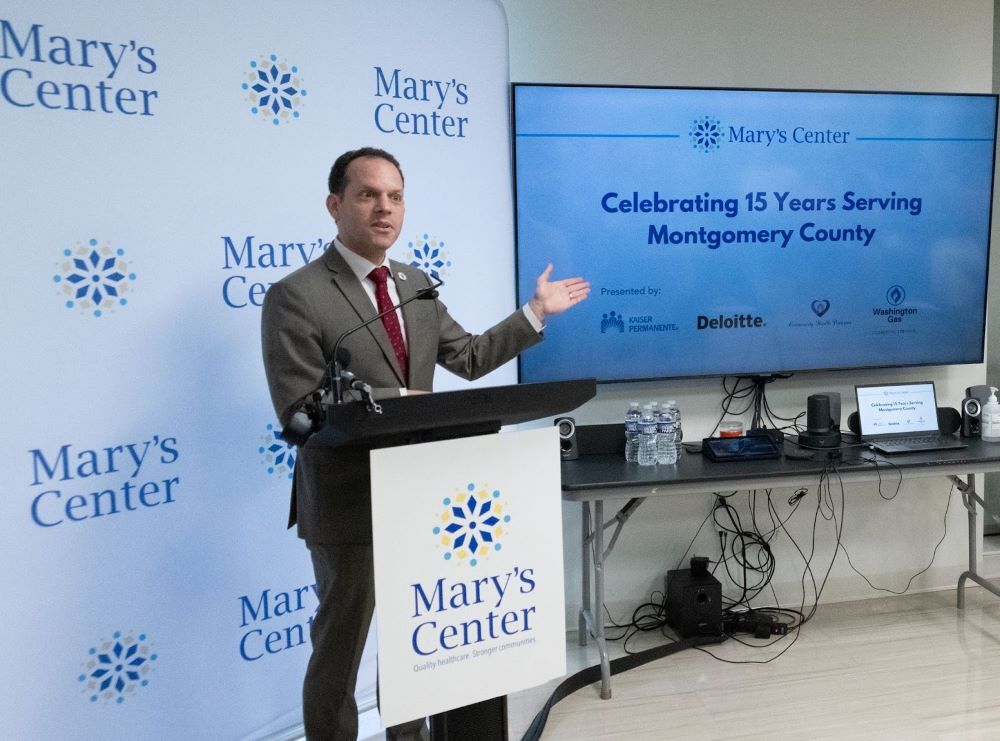 Council President Glass speaks at a podium with the Mary’s Center logo as a backdrop.