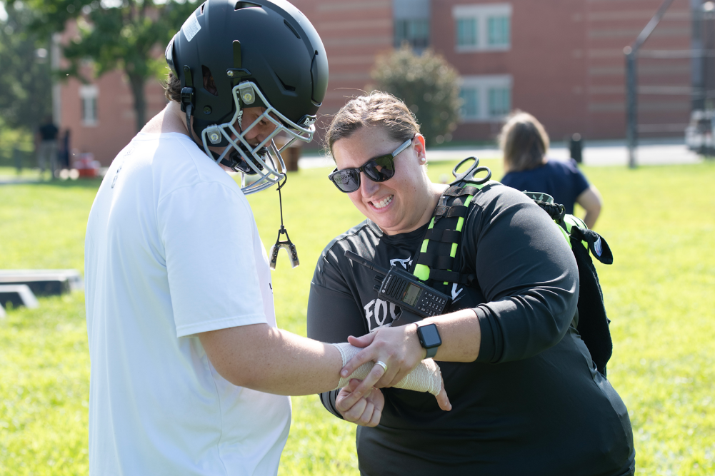 Athletic trainer assists a student athlete on an athletic field. Credit: MCPS.