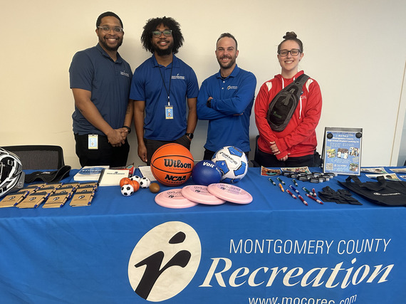 MoCoRec staffers smiling for a picture behind a table at a job fair