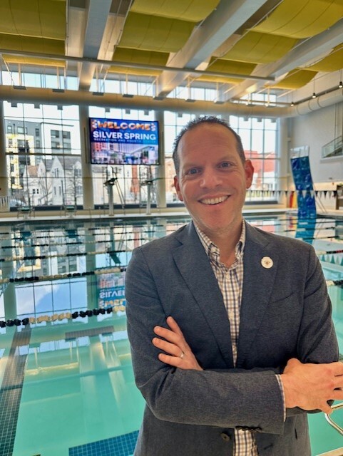 A picture of Councilmember Glass in front of the pool at the new Silver Spring Rec Center