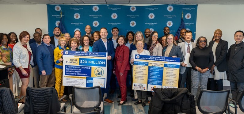 Councilmembers, business and civic leaders pose with poster boards promoting the $20 million economic stimulus.