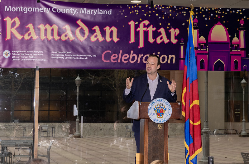 Council President Friedson speaks at a podium in front of the “Montgomery County Ramadan Iftar Celebration” banner.