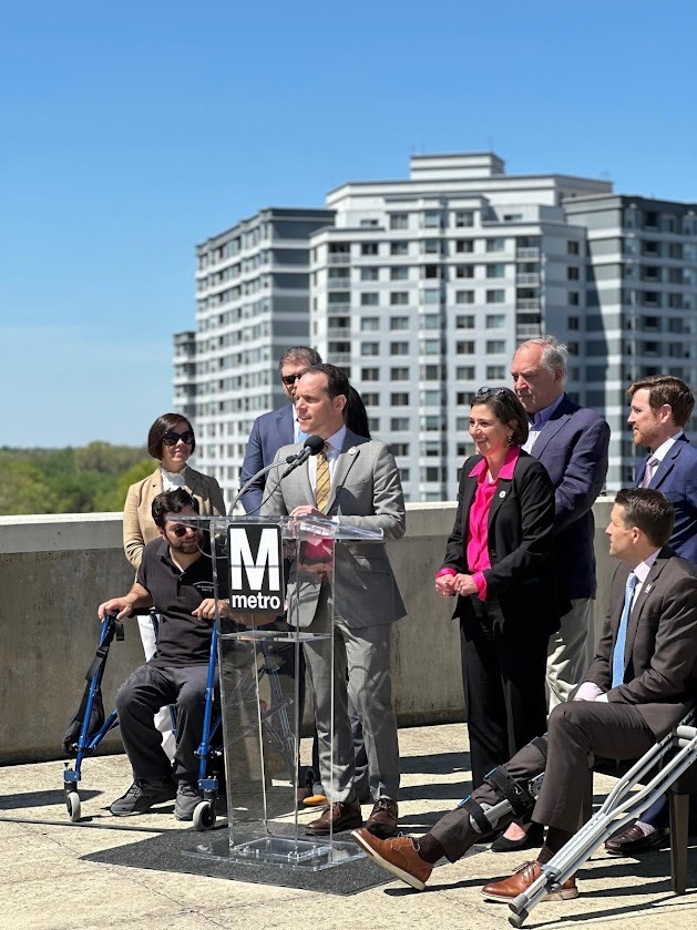 Councilmember Glass speaks at a press conference in front of a Metro sign