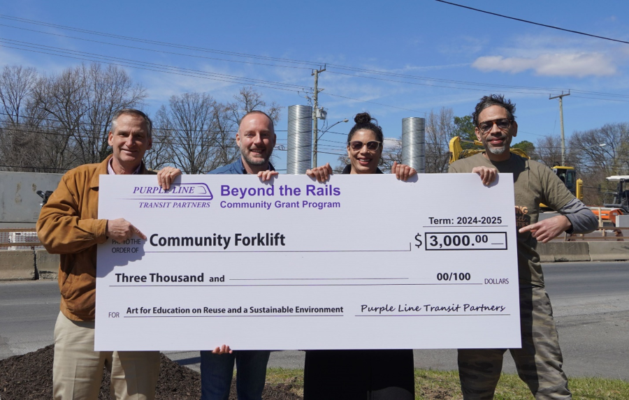 Four business leaders hold a large check for $3,000 as part of the Beyond the Rails Community Grants program.