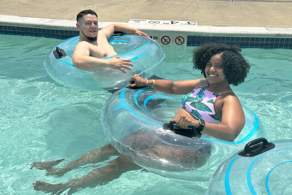 A man and woman smile for a picture while riding tubes down a lazy river at the pool