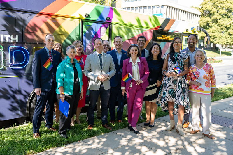 Councilmembers and LGBTQ+ leaders pose in front of the #RideWithPride Ride On bus.