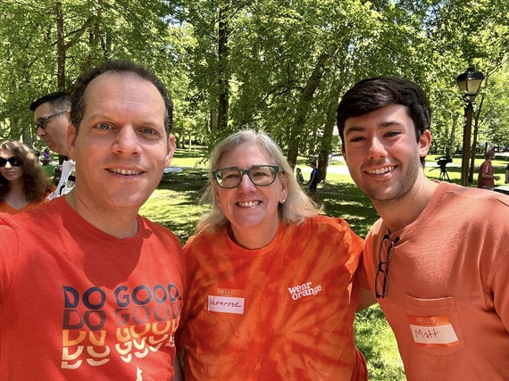 A photo of Councilmember Glass next to two volunteers, all of whom are wearing orange
