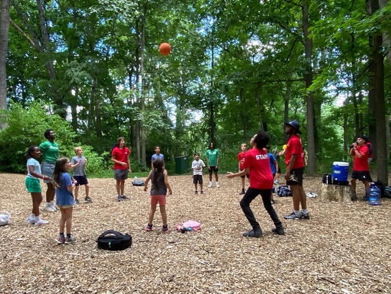 Campers and staff trying to keep a ball in the air while playing in the forest