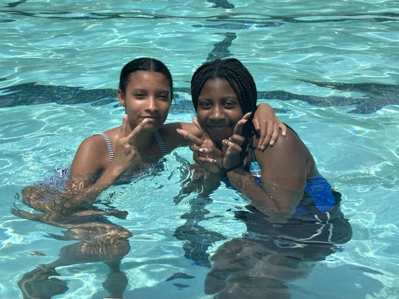 Two girls smiling for a picture while swimming in a pool