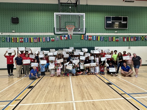 Campers and staff smile for a picture while holding certificates