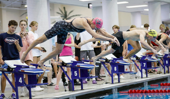 Swimmers jumping into the pool for a race