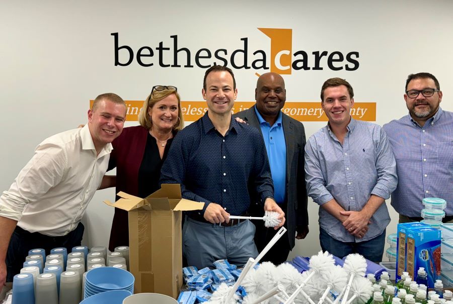 Group photo with Team Friedson and Bethesda Cares team standing at a table with household supplies.