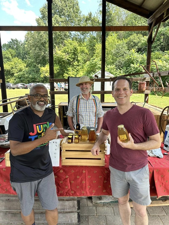 Councilmember Glass holding a bottle of honey with two guests at Button Farm