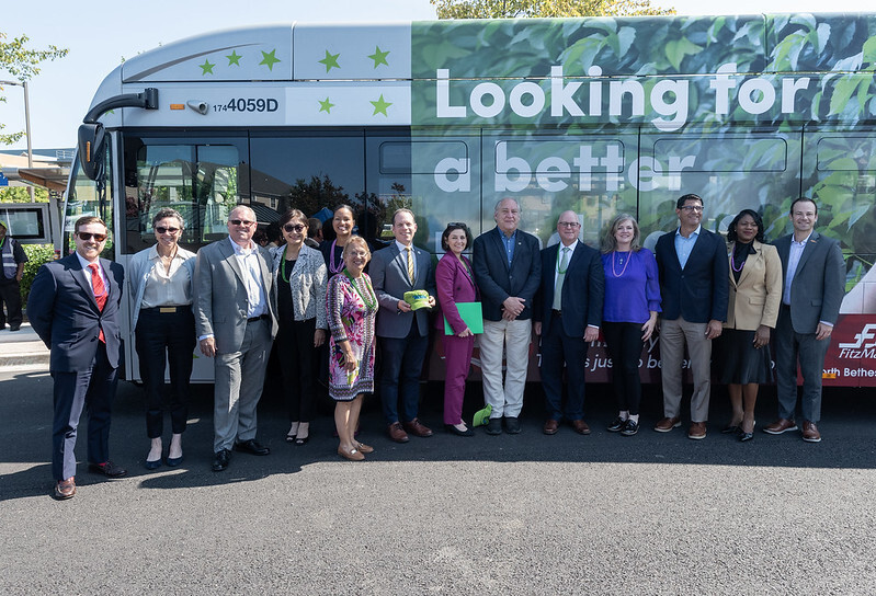 County and state leaders stand in front of a wrapped Ride On extRa bus.