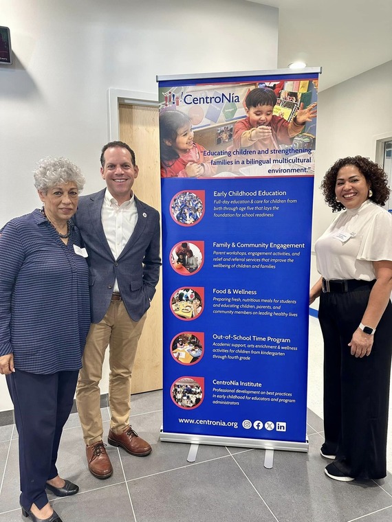 Councilmember Glass stands with two of CentroNia's leaders in front of a banner outlining the center's services