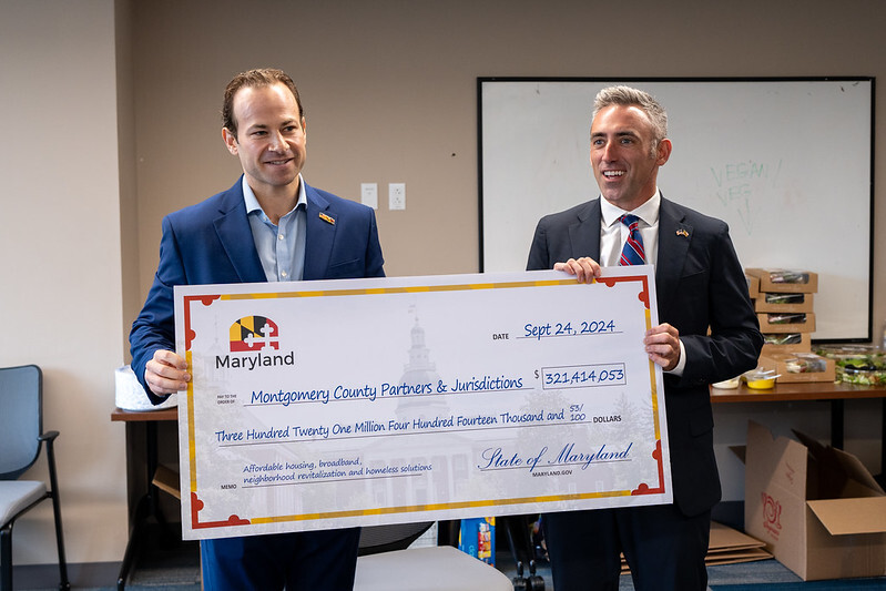 Council President Friedson and Sec. Jake Day pose with a large $321 million check to Montgomery County partners and jurisdictions.