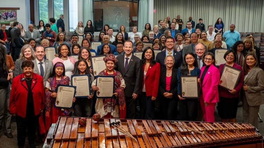 Group photo in the Council chamber in front of a large marimba for Hispanic Heritage Month.