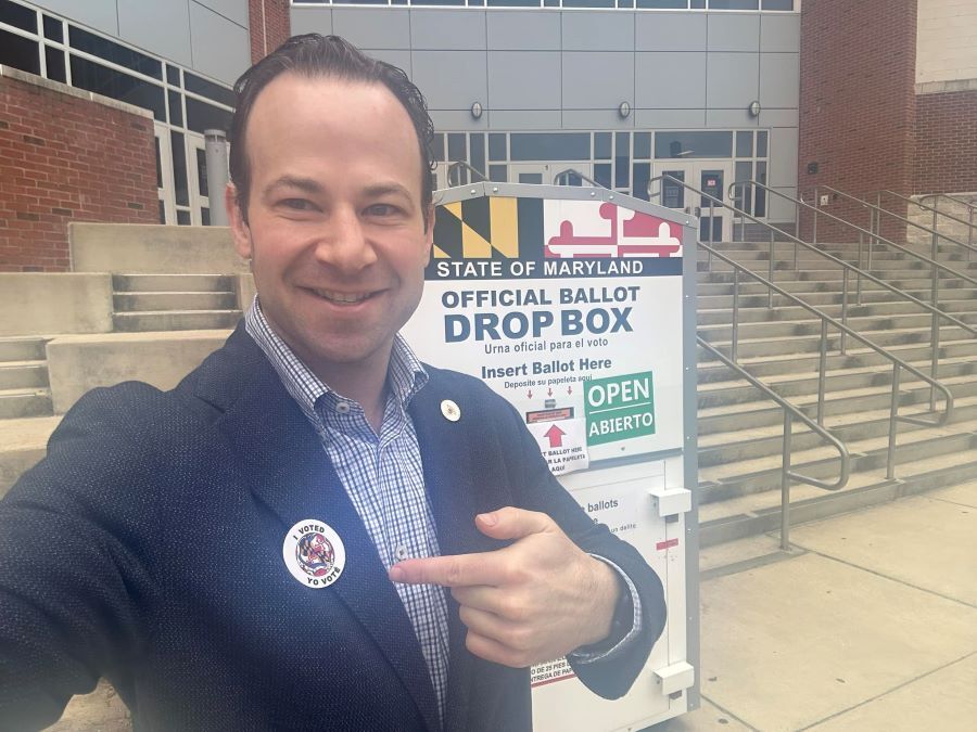 Council President Friedson wearing an “I Voted” sticker in front of a ballot drop box.