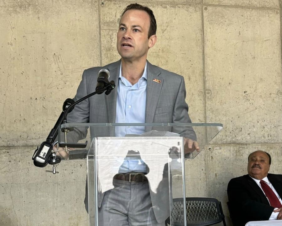 Photo of Friedson speaking at podium with King in the background.