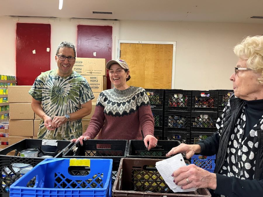 CP Stewart smiling with community members in front of food distribution crates at a Thanksgiving food drive.