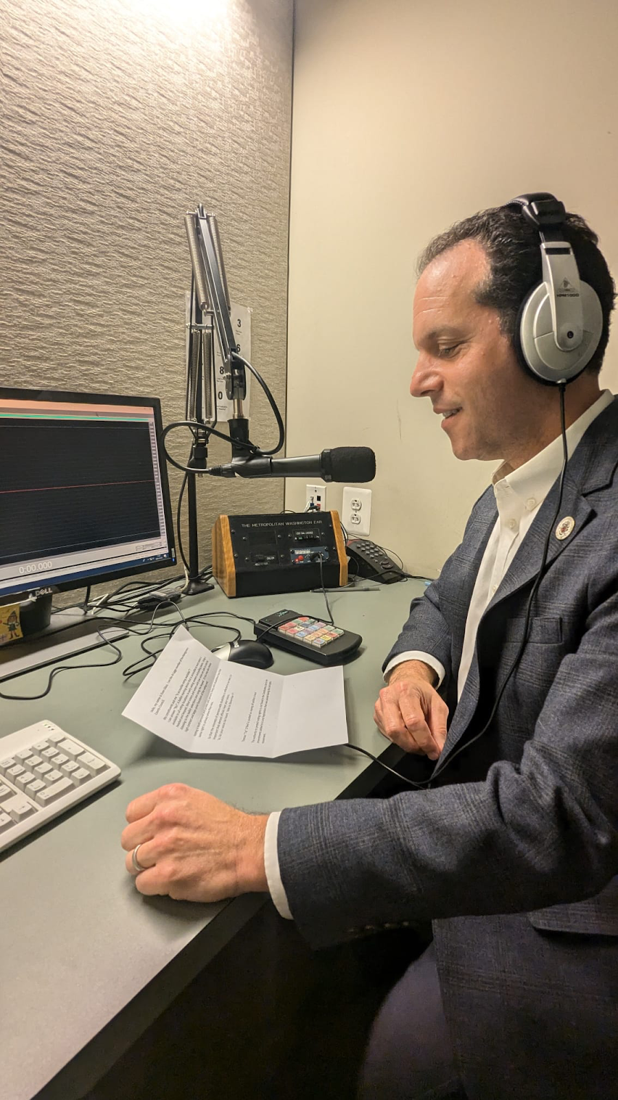 A photo of Councilmember Glass speaking into a radio broadcast microphone