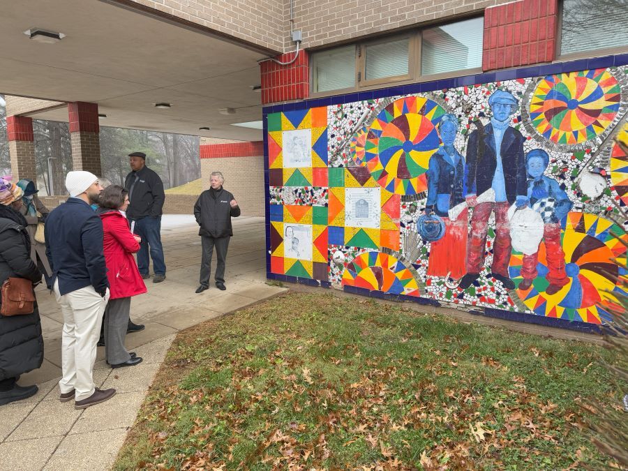 Community members look at a colorful mural at the Upper County Community Center.