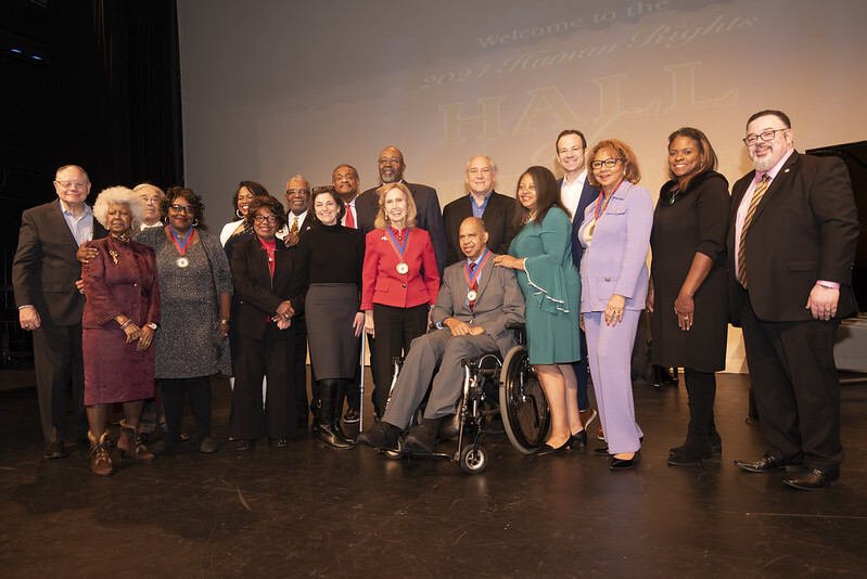 County officials and Hall of Fame honorees pose for a group photo on a stage.